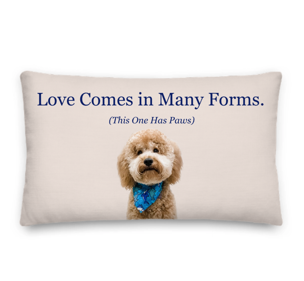 Pillow with a dog and text 'Love Comes in Many Forms. (This One Has Paws)' on a beige background
