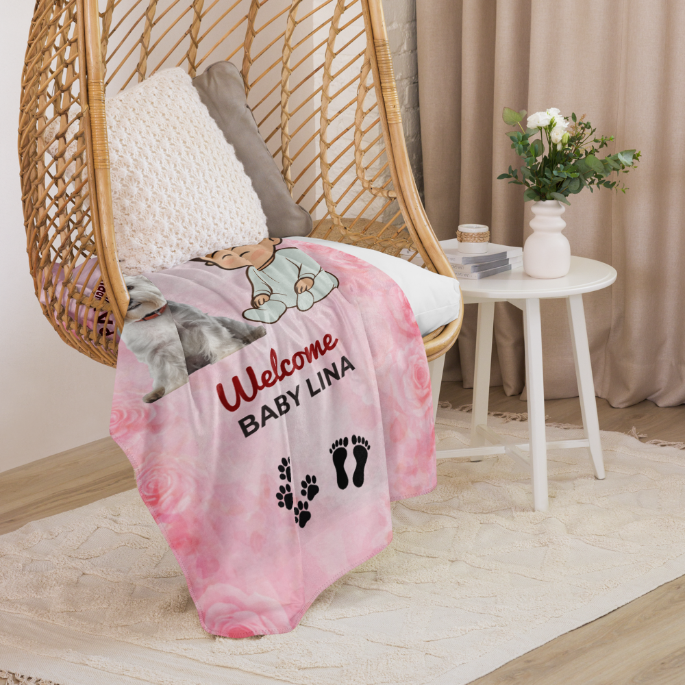 Pink baby blanket with personalized text on a wicker chair in a room setting.